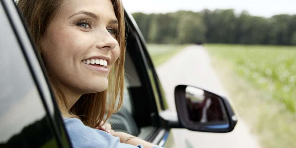 Una giovane donna ammira il paesaggio da un’auto: la mobilità sostenibile è sempre più importante per l’ambiente