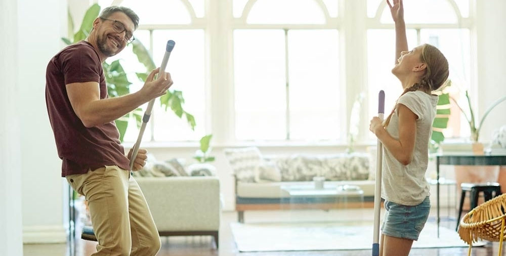 Una coppia si diverte usando spazzole e scope come chitarre, mentre fa pulizie green di primavera