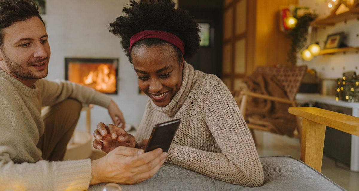 Un ragazzo mostra a una ragazza uno smartphone, strumento fondamentale per controllare i consumi e ridurre le emissioni di gas serra
