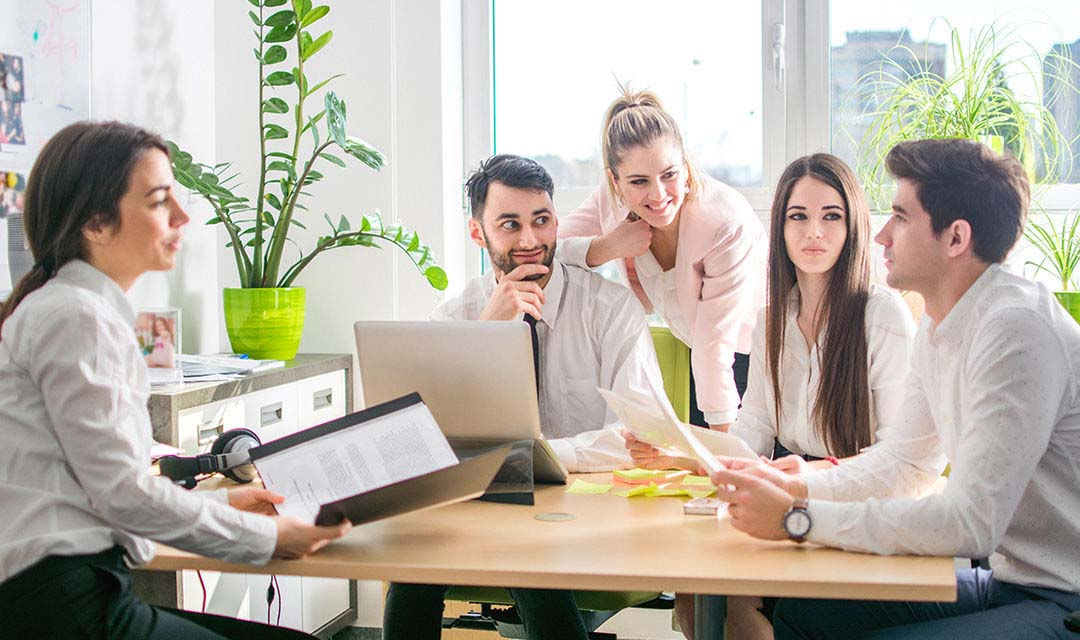 Un gruppo di giovani lavoratori discute alcuni report intorno a un tavolo