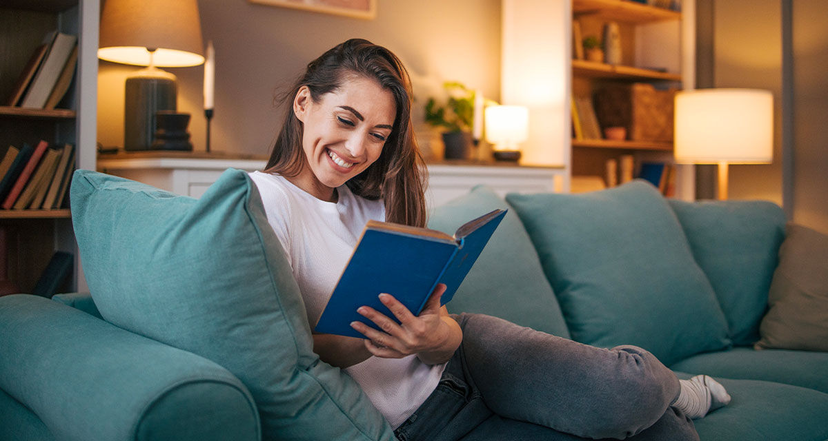 Una ragazza rilassata su un divano legge un libro: la flessibilità energetica permette il miglior comfort domestico