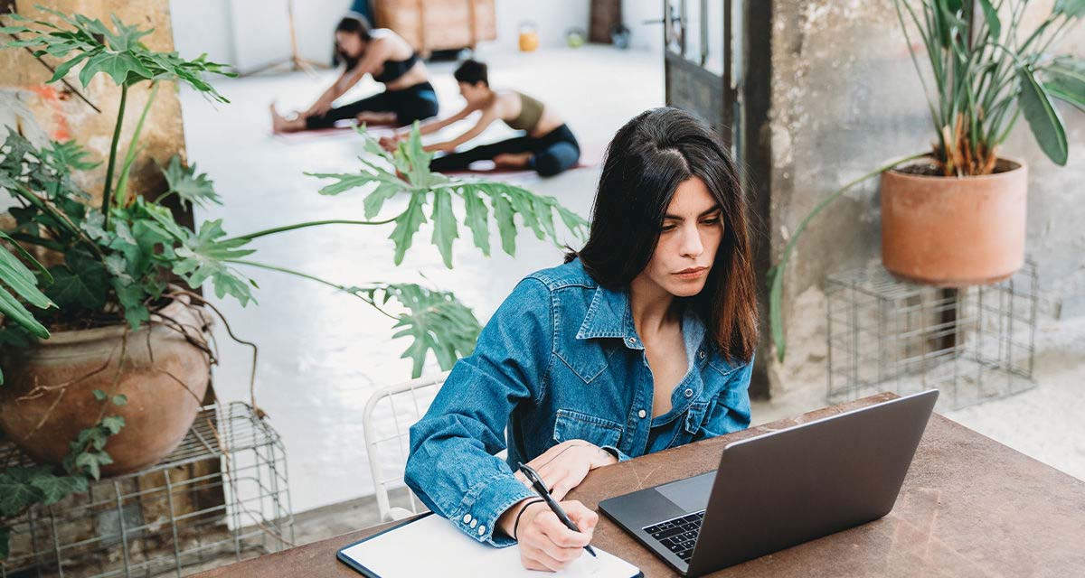 Una ragazza prende appunti mentre è al computer in uno spazio condiviso