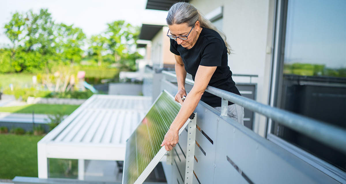 Una donna installa da sola un pannello fotovoltaico sul balcone
