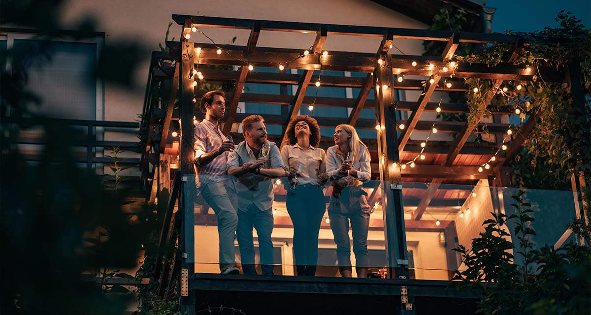 Un gruppo di amici si gode un balcone illuminato: guida all’allaccio luce seconda casa